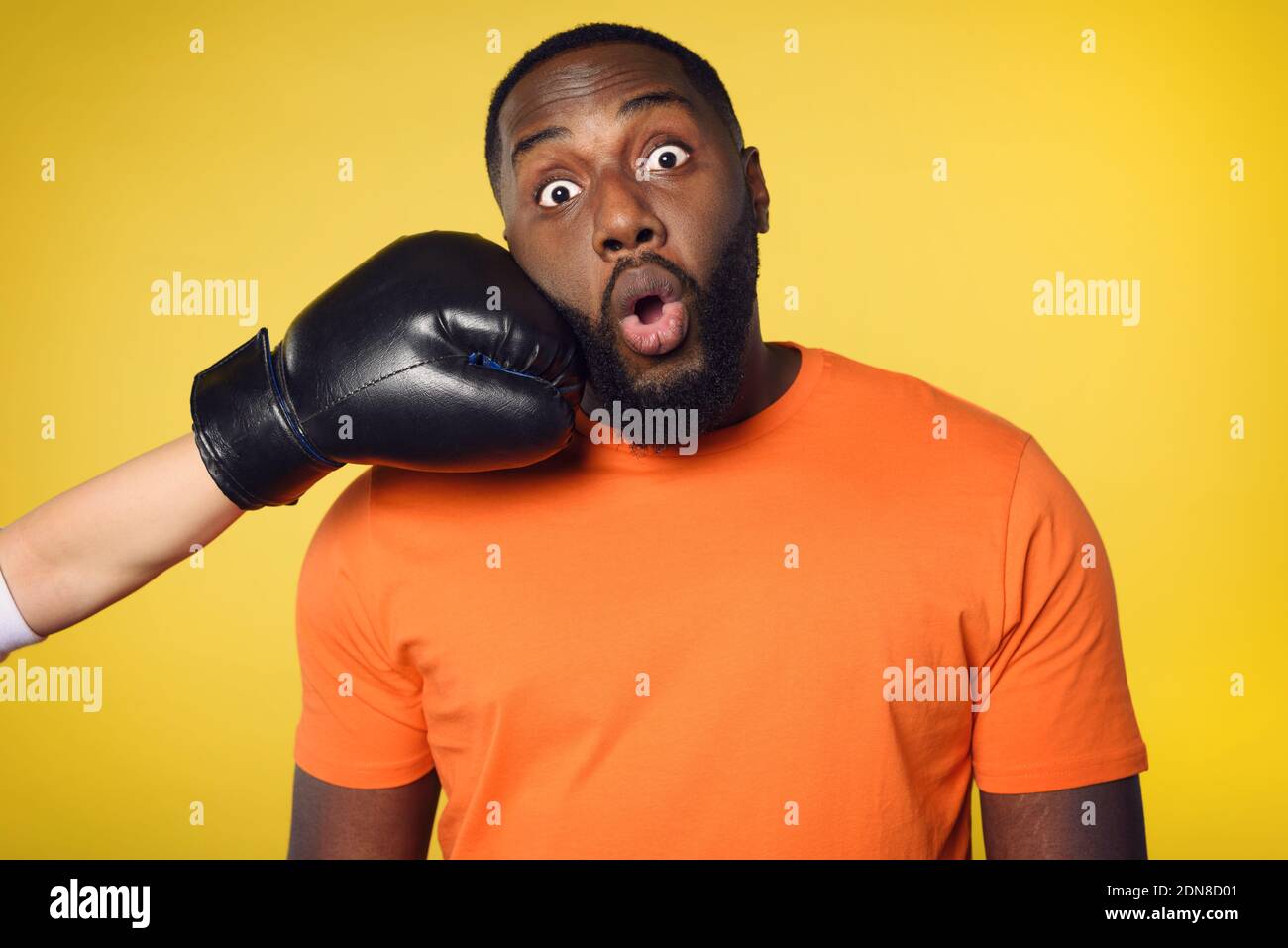 Schockiert schwarzen Mann erhält einen Schlag von jemandem. Gelber Hintergrund Stockfoto
