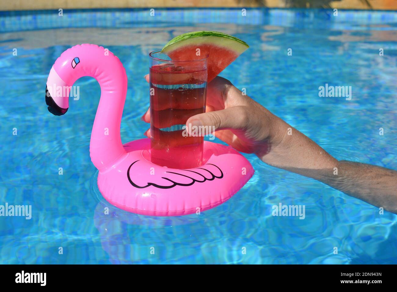 Frau, die einen Cocktail hält, schwimmt in einem aufblasbaren Pink Flamingo  Getränkehalter in EINEM Swimmingpool Stockfotografie - Alamy
