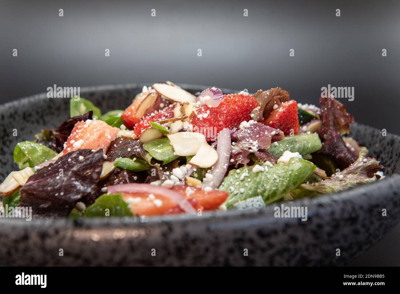 Schüssel Sala mit Käse und in Scheiben geschnittenen Mandeln und viel Nahrung gekrönt. Stockfoto