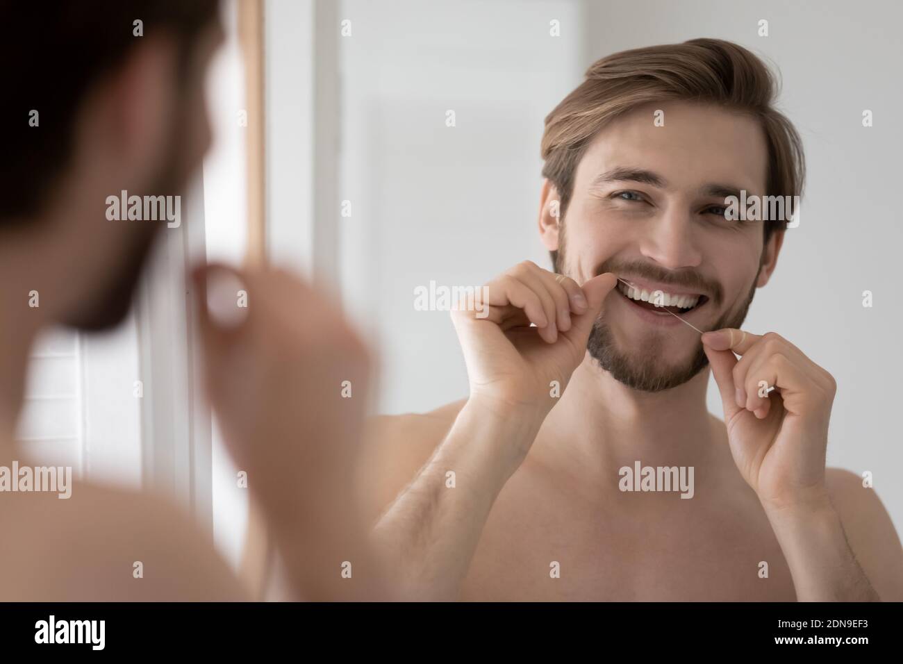 Happy Millennial Mann Reinigung Zähne mit Zahnseide. Stockfoto