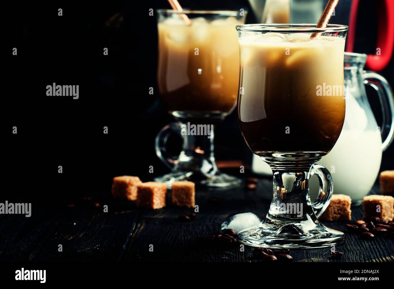 Eiskaffee im Glas, Milch, Zucker und Kaffeemaschine, dunkler Hintergrund, selektiver Fokus Stockfoto