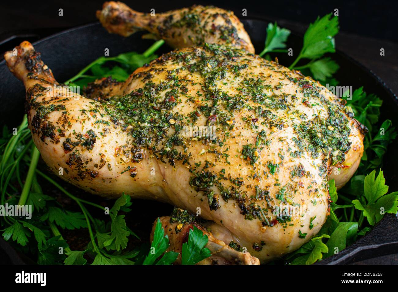 Chimichurri Brathähnchen: Ein ganzes Huhn in einer gusseisernen Pfanne mit Chimichurri-Sauce gebraten Stockfoto