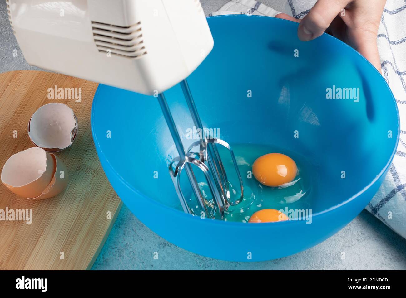 Frische Hühnereier in einer blauen Schüssel verquirlen Stockfoto