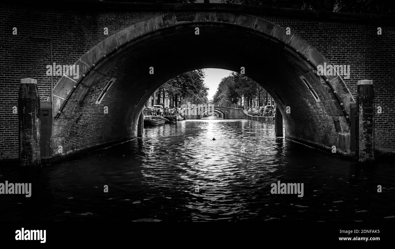 Schwarz-Weiß-Foto von Ansicht von sieben historischen Brücken in einer geraden Linie über die Reguliersgracht, von einem Kanalboot in der Herengracht aus gesehen Stockfoto