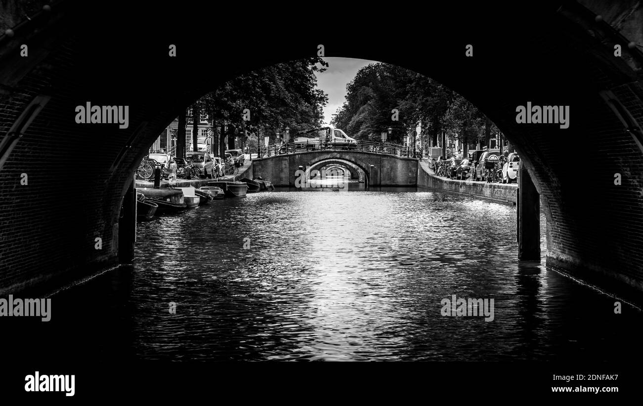 Schwarz-Weiß-Foto von Ansicht von sieben historischen Brücken in einer geraden Linie über die Reguliersgracht, von einem Kanalboot in der Herengracht aus gesehen Stockfoto