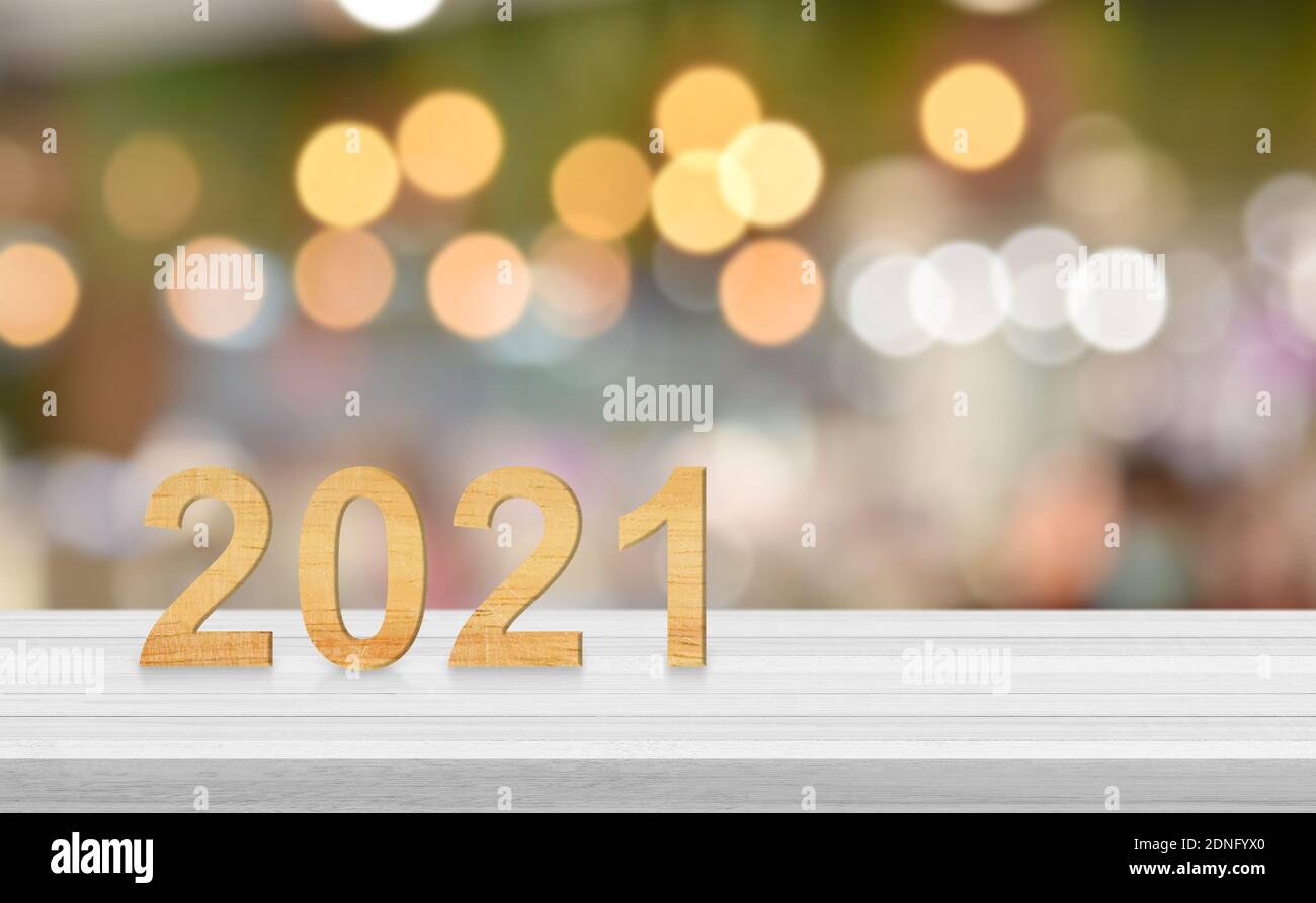 Hölzerne Zahl auf weißem Holztisch über verwischen Bokeh hellen Hintergrund, kopieren Raum für Text. Idee für ein glückliches neues Jahr 2021 Grußkarte, Banner. Stockfoto