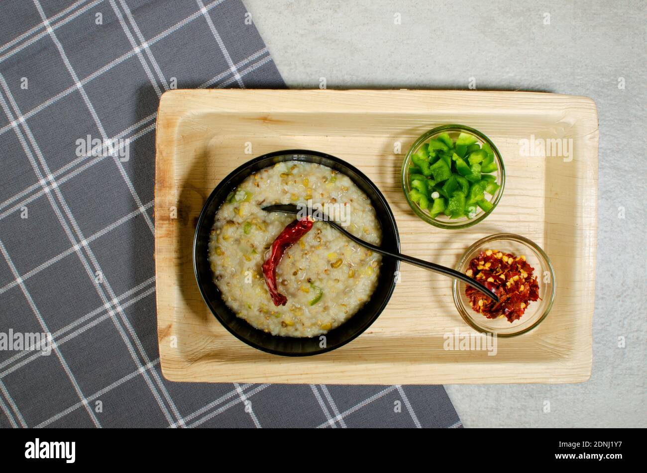 Cooked Dalia in Black Bowl, capsicum  and red chilli flakes in  glass bowl. Bulgar wheat, Broken wheat or cracked wheat or couscous is made by milling Stockfoto