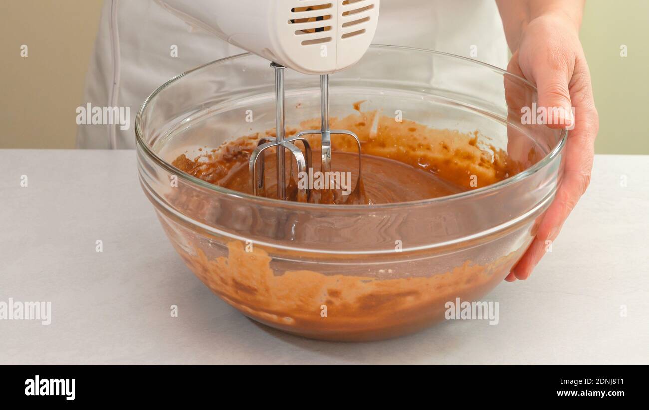 Mischen von Schokoladenteig mit einem elektrischen Mixer. Schokolade Muffins oder Schokolade Cupcakes Rezept Stockfoto
