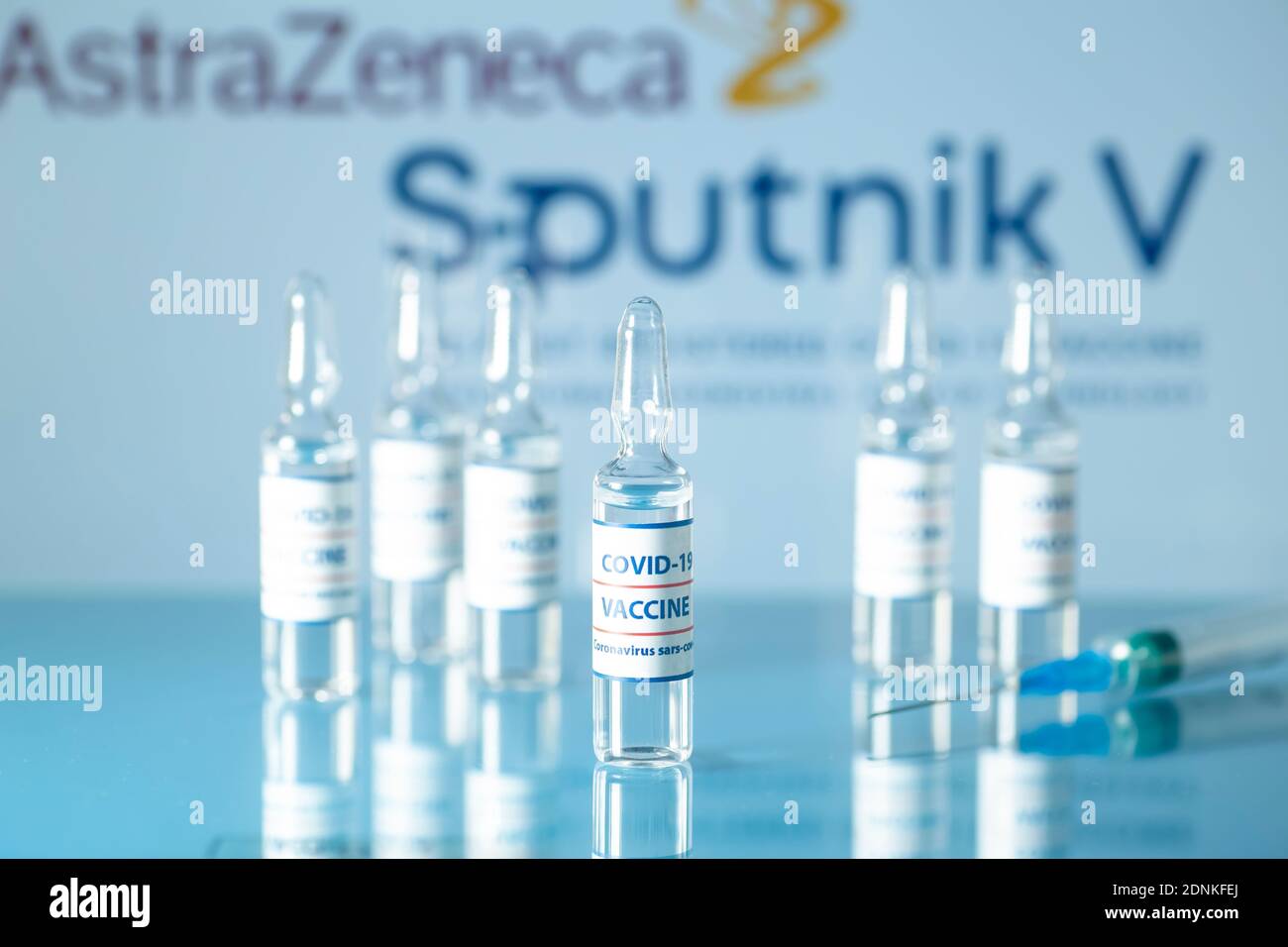 Sputnik 5 und AstraZeneca gegen COVID-19. Medizinische Glasfläschchen mit Flüssigkeit auf dem Hintergrund. Sputnik V und AstraZeneca Logo. Ampullen mit Stockfoto