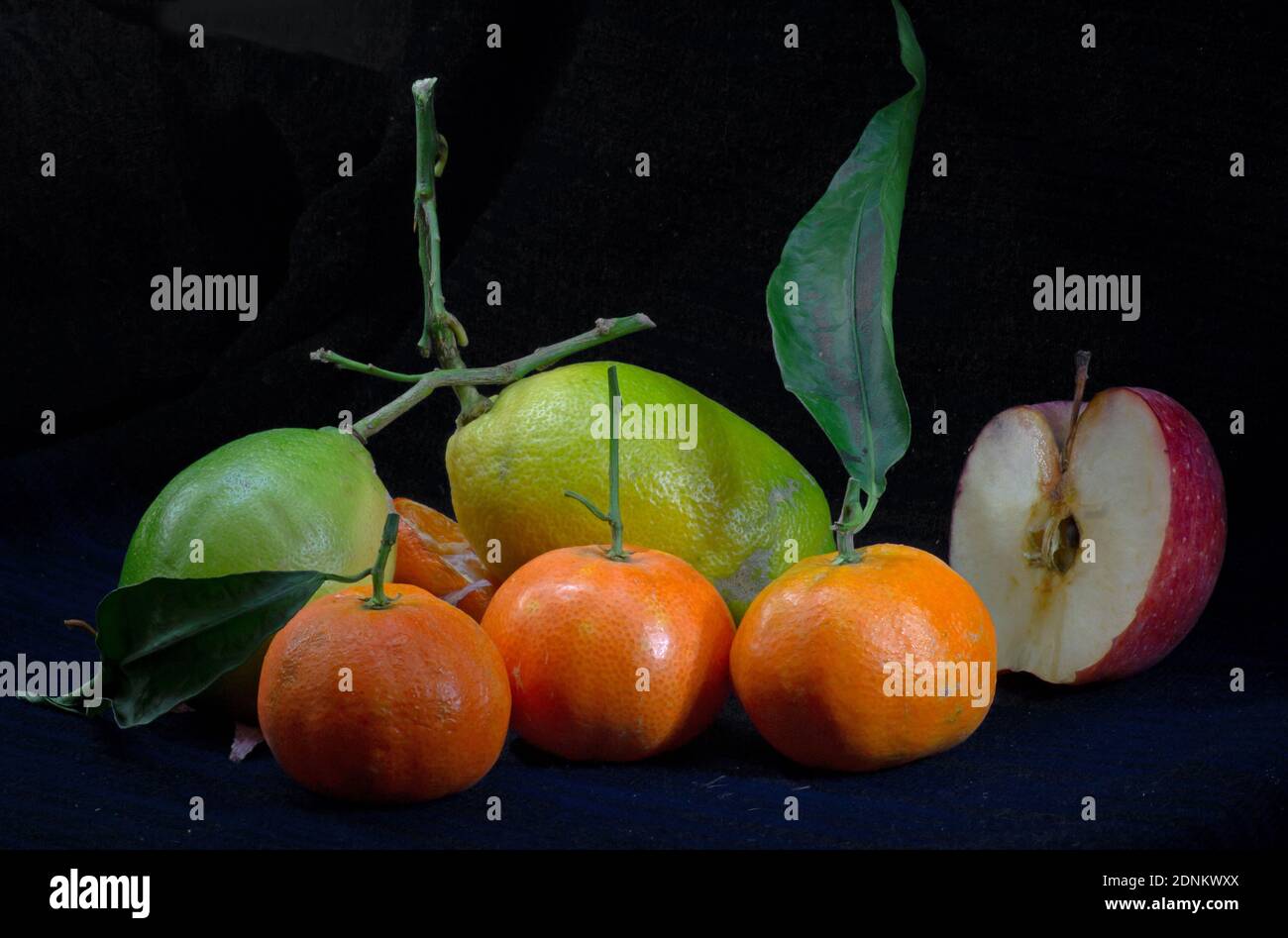 Gemischte Zusammensetzung aus Mandarine und Zitrone mit einem halben Apfel Auf dunklem Hintergrund Stockfoto