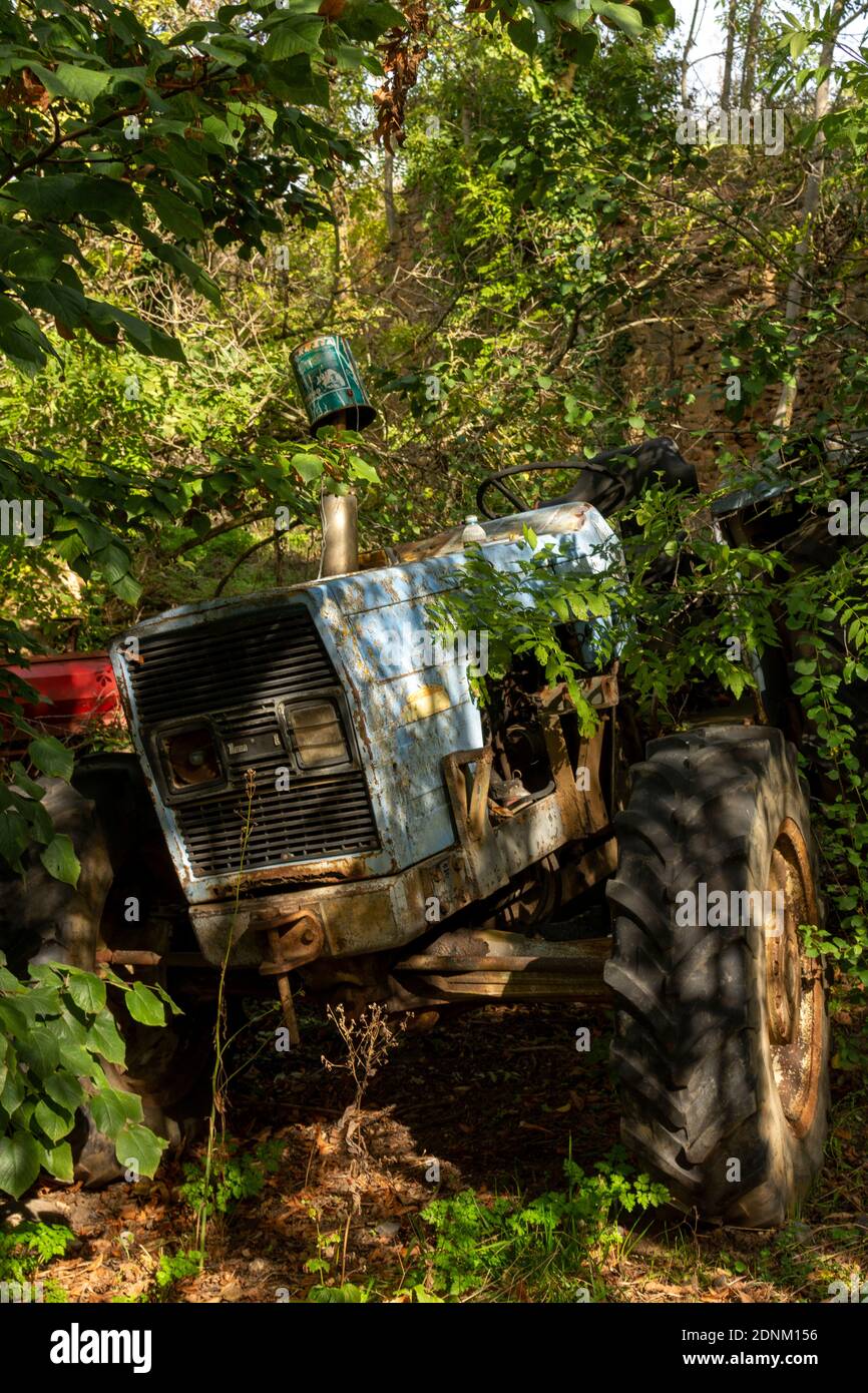 Ein alter, verlassener Traktor, der mit Vegetation bewachsen ist, in einer ländlichen Umgebung. Frankreich. Europa. Stockfoto