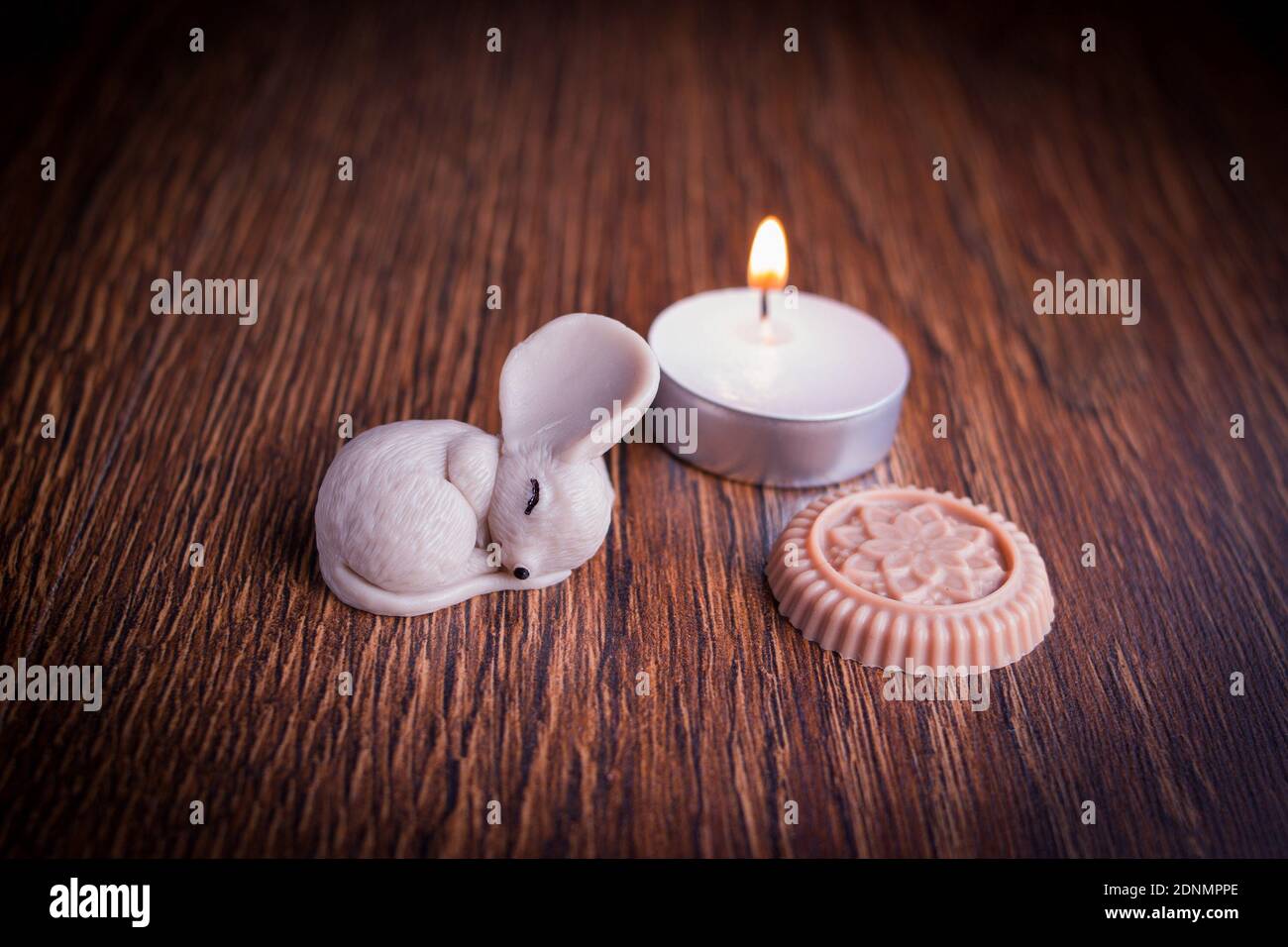 Foto dekorative schlafende Maus Figur mit brennender Kerze auf Holz Hintergrund Stockfoto Foto dekorative schlafende Maus Figur mit brennender Kerze auf Holz Hintergrund Stockfoto