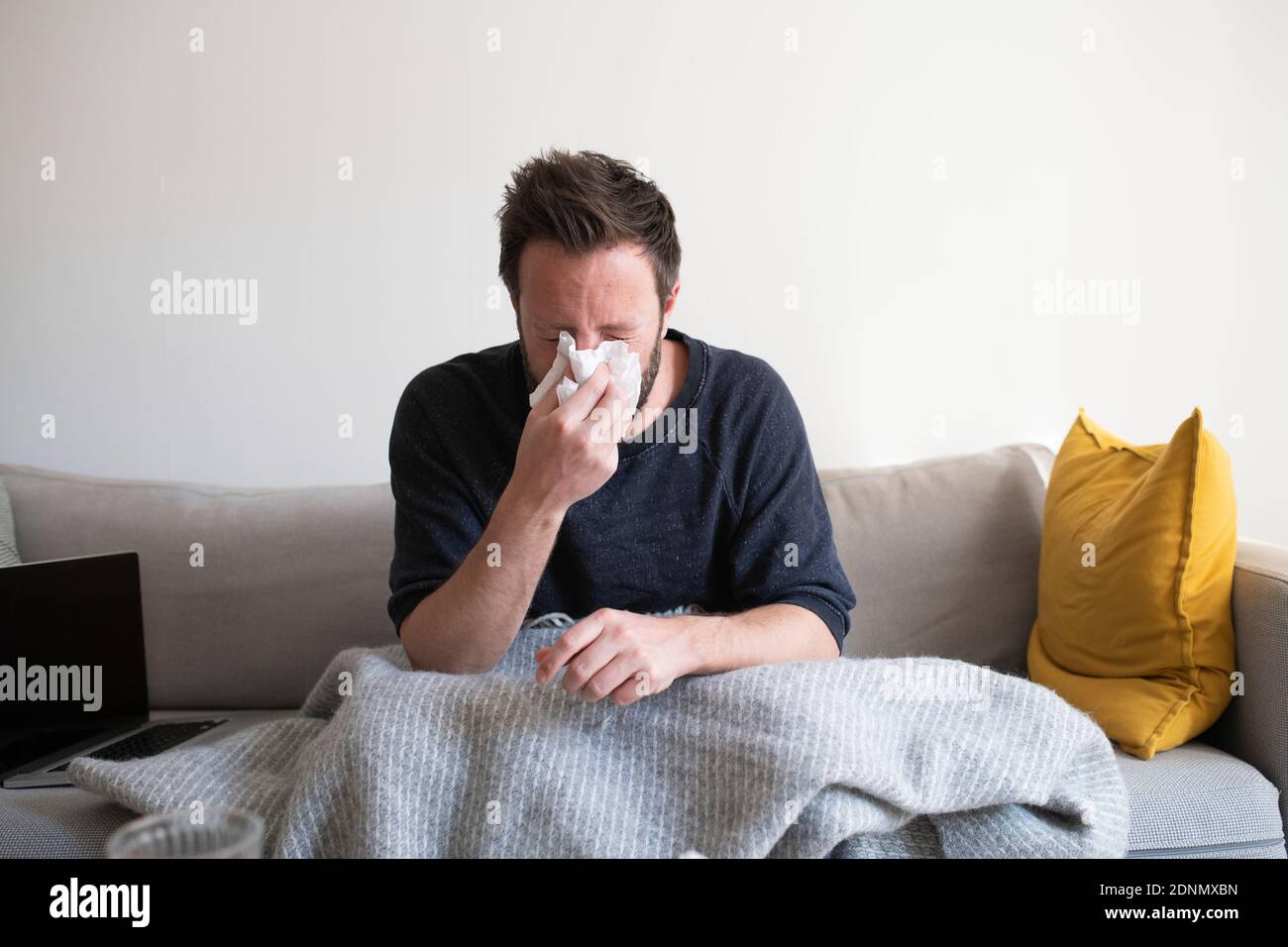 Mann auf dem Sofa bläst seine Nase Stockfoto