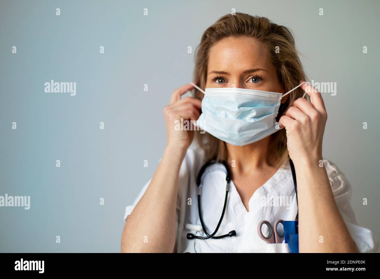 Ärztin, die Schutzmaske aufsetzt Stockfoto
