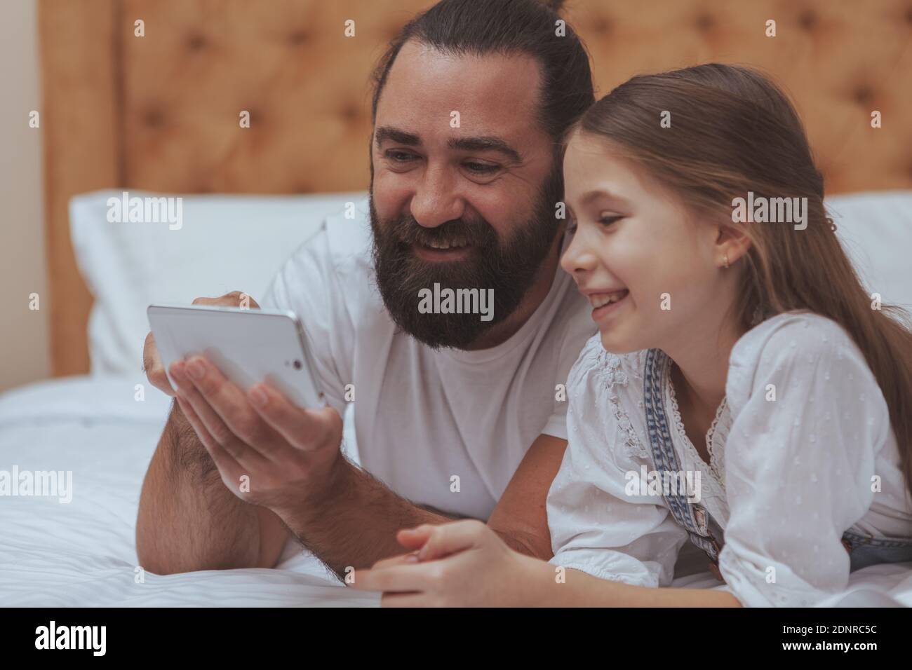 Nahaufnahme eines hübschen bärtigen reifen Mann genießen mit Smartphone mit seiner liebenswert kleine Tochter. Alleinerziehender Vater, der seinem Kind beibringt, wie man in benutzt Stockfoto