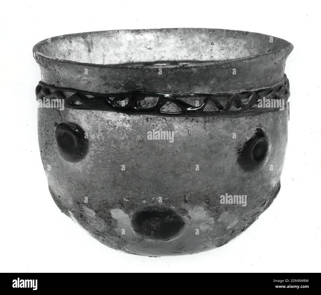 Schale mit grünen Schälchen, ehemals Glas, mundgeblasen, Fadenstütze, Glas, Gesamt: Höhe: 9.5 cm; Durchmesser: 12 cm, Spätantike, Römische Antike, die halbkugelförmige Schale besteht aus transparentem, hellgrünem Glas. Der Rand ist leicht nach außen gebogen, die Mitte des Bodens ist leicht konkav. Als Dekoration dienen acht runde dunkelgrüne Noppen. Unterhalb des Randes verläuft ein Band dunkelgrüner Fäden, von denen der mittlere in einer Zickzacklinie zwischen zwei horizontalen Fäden verschmolzen ist Stockfoto
