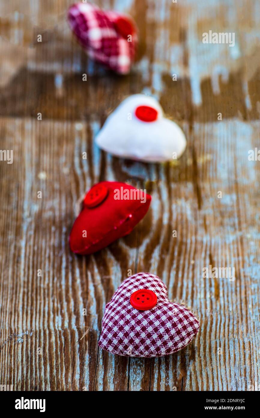 Vier ornamentale Stoffherzen in einer Reihe auf einem Holz Tabelle Stockfoto