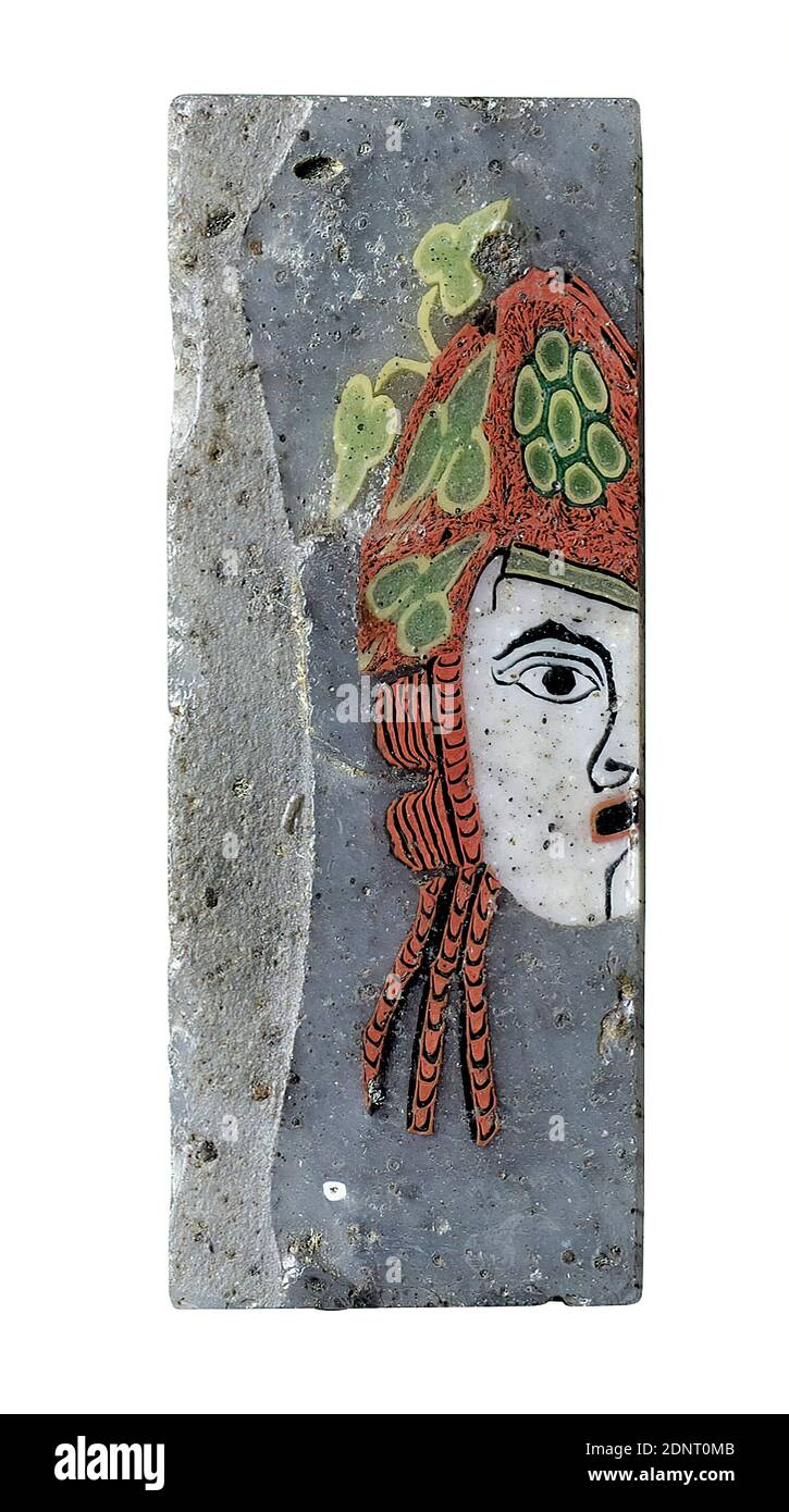 Mosaikglasstein mit Darstellung einer Theatermaske, Glas, Mosaikglas, mundgeblasen, Fadenglas, gepresst, Glas, Gesamt: Höhe: 3.4 cm; Breite: 1.3 cm; Tiefe: 0.3 cm, Bodenbeläge, Wanddekoration, Theater, Theateraufführung, Theaterkostüm, Maske, Geschichte des Bacchus (Dionysos), frühkaiserliche Zeit, das hohe rechteckige grau-blaue Mosaikglas zeigt in hellen Farben die linke Gesichtshälfte einer weiblichen Theatermaske. Der Mund ist aufgerissen, die Augen sind weit geöffnet. Das hochgestapelte, lockige rote Haar wird von einem grün-gelben Stirnband gehalten. Stockfoto