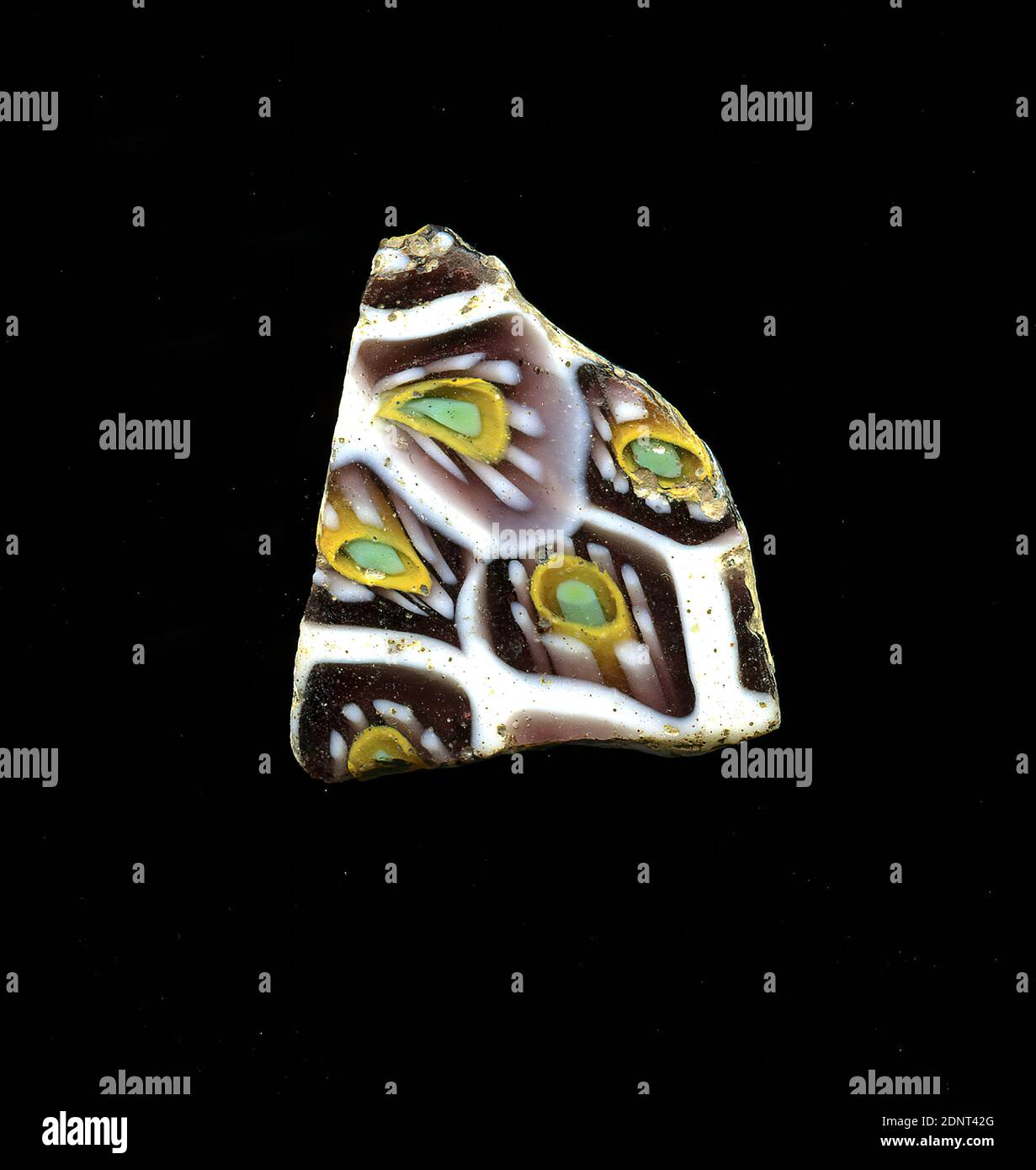 Fragment eines Gefäßes, Glas, millefiori-Technik, Gesamt: Höhe: 1.80 cm; Breite: 2.20 cm, Behälter, Lagerung, Küchenarbeit, Blumenschmuck, frühkaiserliche Zeit, EINE leichte Krümmung des Glassfragmentes ermöglicht die Zuordnung zu einem Gefäß, möglicherweise einer Schüssel. Das violette Glas läuft durch ein unregelmäßiges Raster aus weißen Linien, die einer Wabe ähneln. In den Räumen zwischen den Linien ist eine Blume in millefiori-Technik. Um einen türkisfarbenen Punkt mit einer transparenten und gelben Umrandung herum sind mehrere weiße Punkte, die Blütenblätter darstellen, in einem Kreis zu sehen. Stockfoto