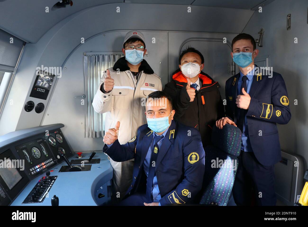 Taschkent, Usbekistan. Dezember 2020. Chinesische Techniker posieren für ein Foto mit usbekischen Fahrern auf einer elektrischen Lokomotive in Taschkent, Usbekistan, 17. Dezember 2020. Usbekistan erhielt am Donnerstag die erste Charge von vier schweren und umweltfreundlichen Elektrolokomotiven von seinen chinesischen Lieferanten. Usbekistan erhält insgesamt 30 Elektrolokomotiven aus China, die sowohl für den Personen- als auch für den Güterverkehr konzipiert sind, darunter 24 im Rahmen eines Vertrags im Wert von 134 Millionen US-Dollar, der 2019 unterzeichnet wurde, und sechs weitere, die Anfang dieses Jahres gekauft wurden. Quelle: Zafar Khalilov/Xinhua/Alamy Live News Stockfoto