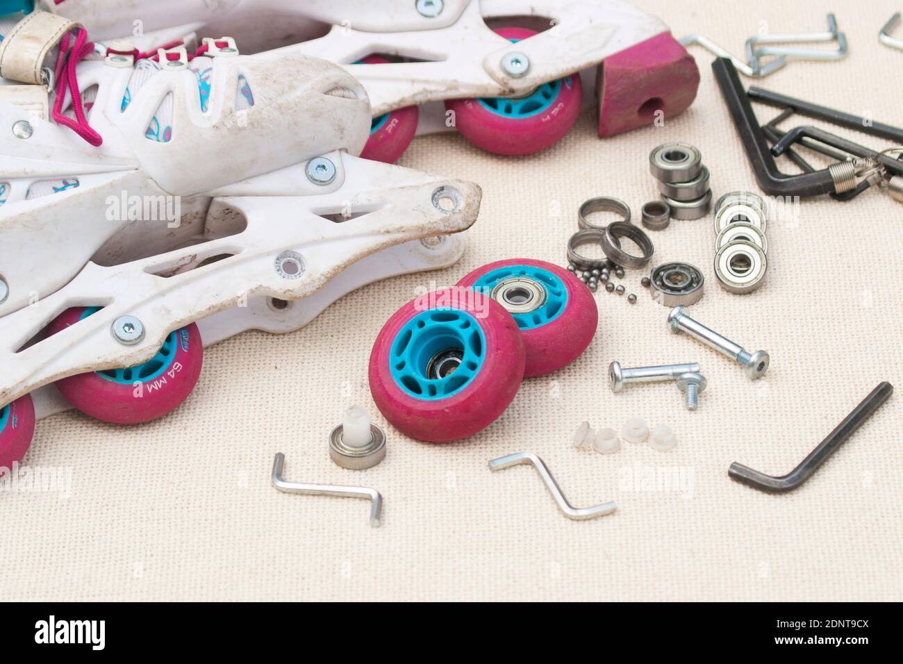 Austausch des Schlittschuhrollenlagers. Demontierte Rollschuhe, neue und verschlissene Lager, Achsen, Buchsen, Schrauben und Sechskantschlüssel. Stockfoto