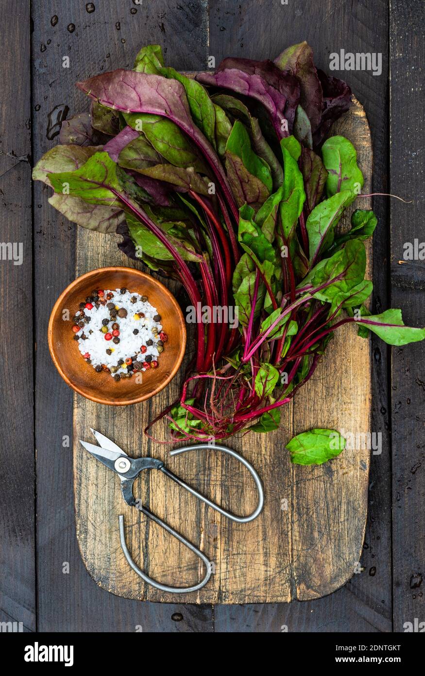 Rote Bete Blätter mit Meersalz und Pfefferkörner auf einem Hacken Platine Stockfoto