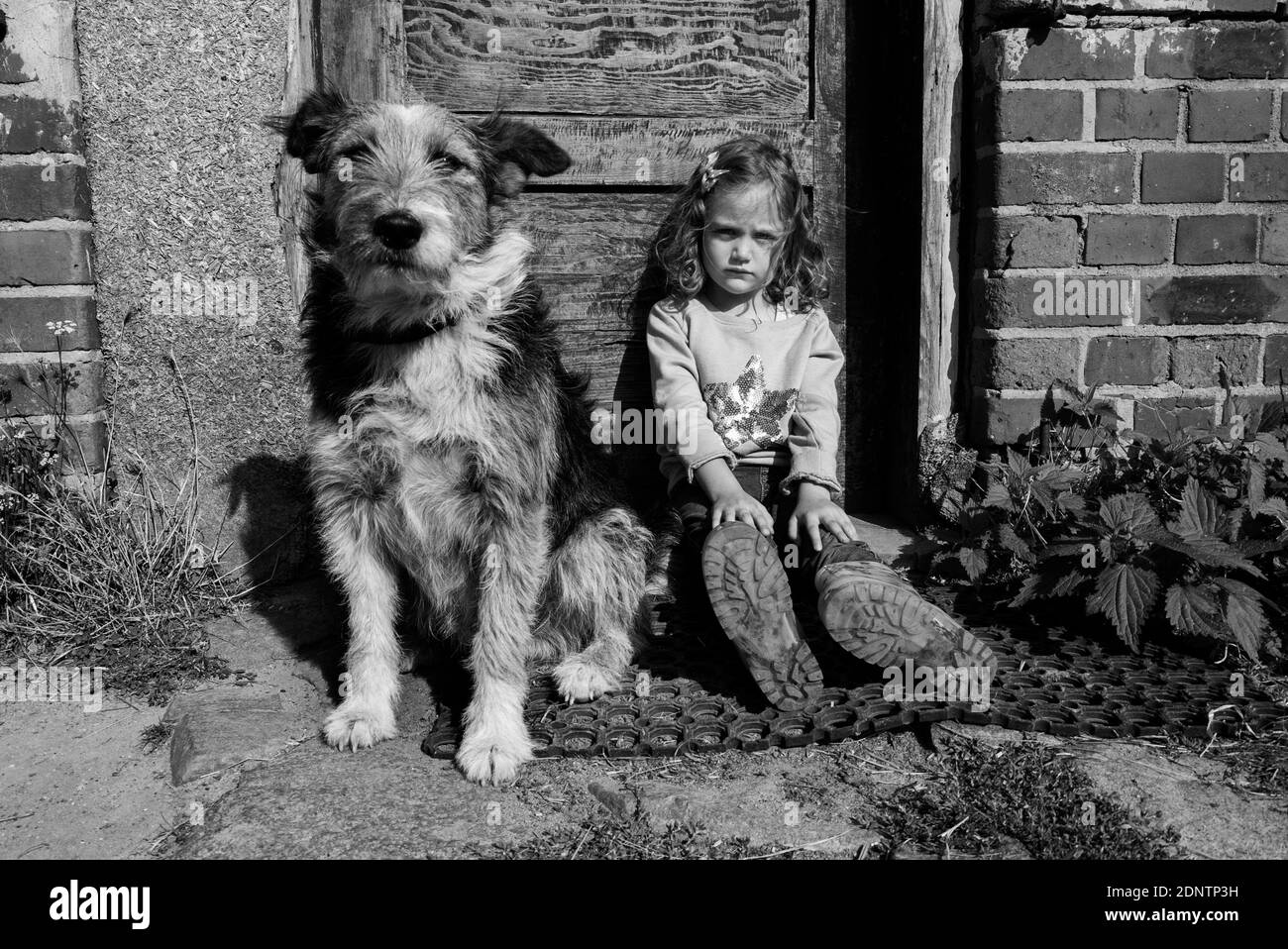 Mädchen sitzt vor der Haustür mit ihrem Hund, Polen Stockfoto
