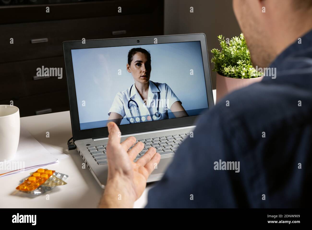 Online Arztberatung - Mann im Gespräch mit Arzt auf Laptop Zu Hause während eines Telemedizin-Videoanrufs Stockfoto