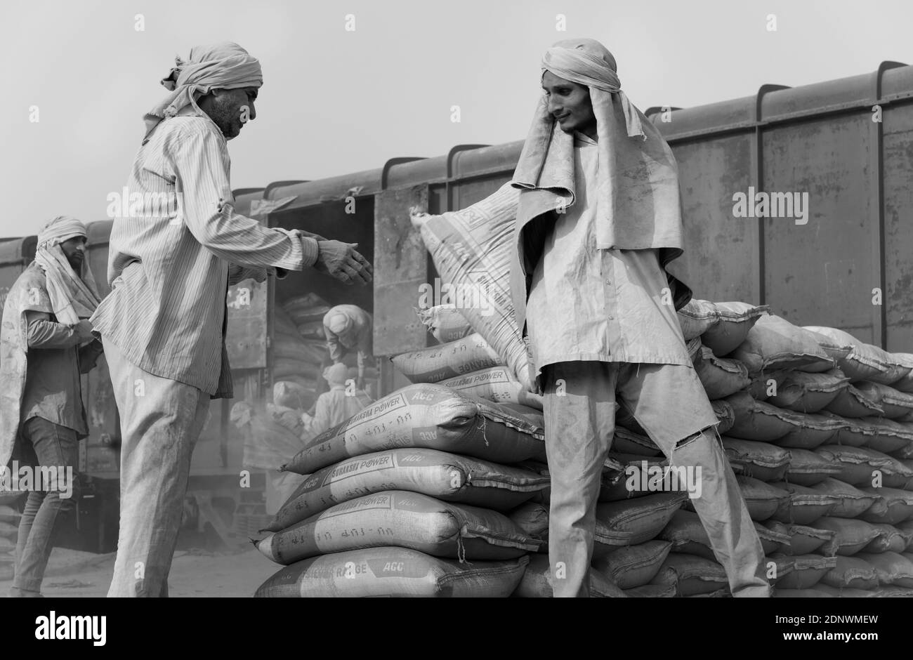 Mann trägt nur Kopftuch als Schutz eingesetzt, um Taschen aus Zement von der Bahn auf Lastwagen in Mathura, Uttar Pradesh, Indien zu bewegen. Stockfoto