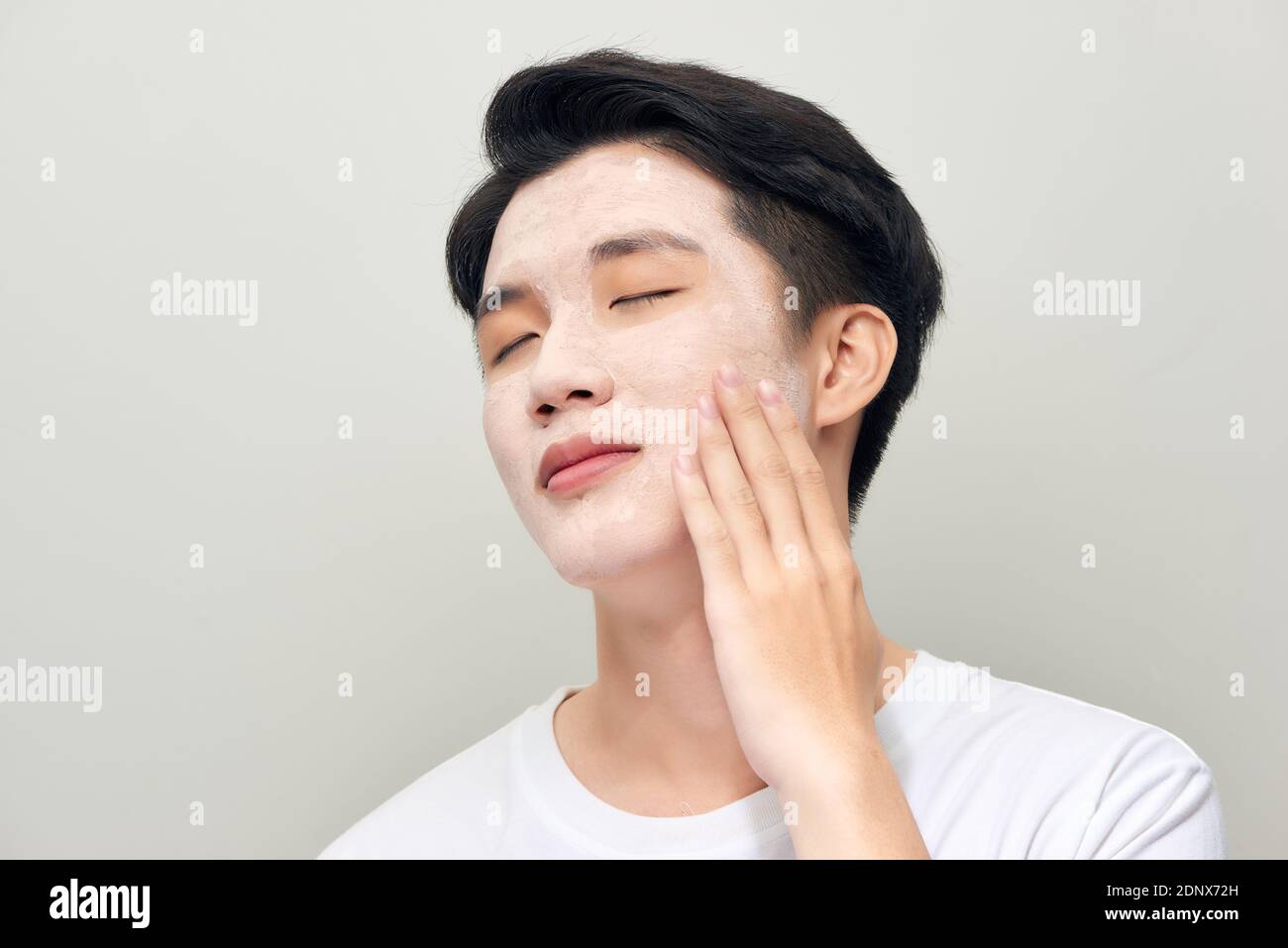 Portrait eines schönen jungen Mannes mit einer Gesichtsmaske aus Ton, Gesichtsbehandlung. Stockfoto