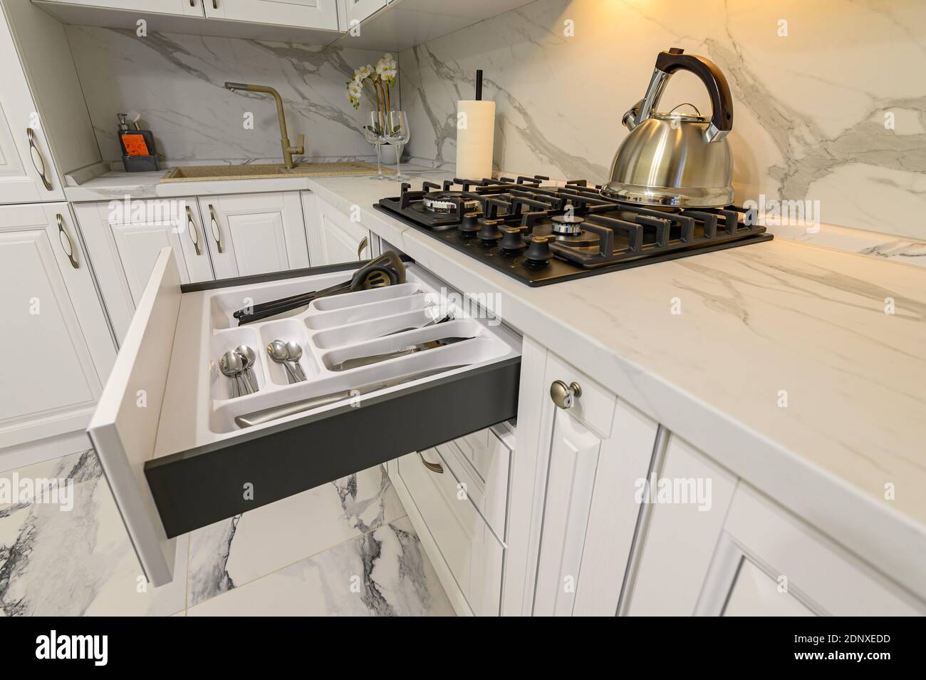Offene Schubladen mit Geschirr in der modernen weißen Küche Stockfoto
