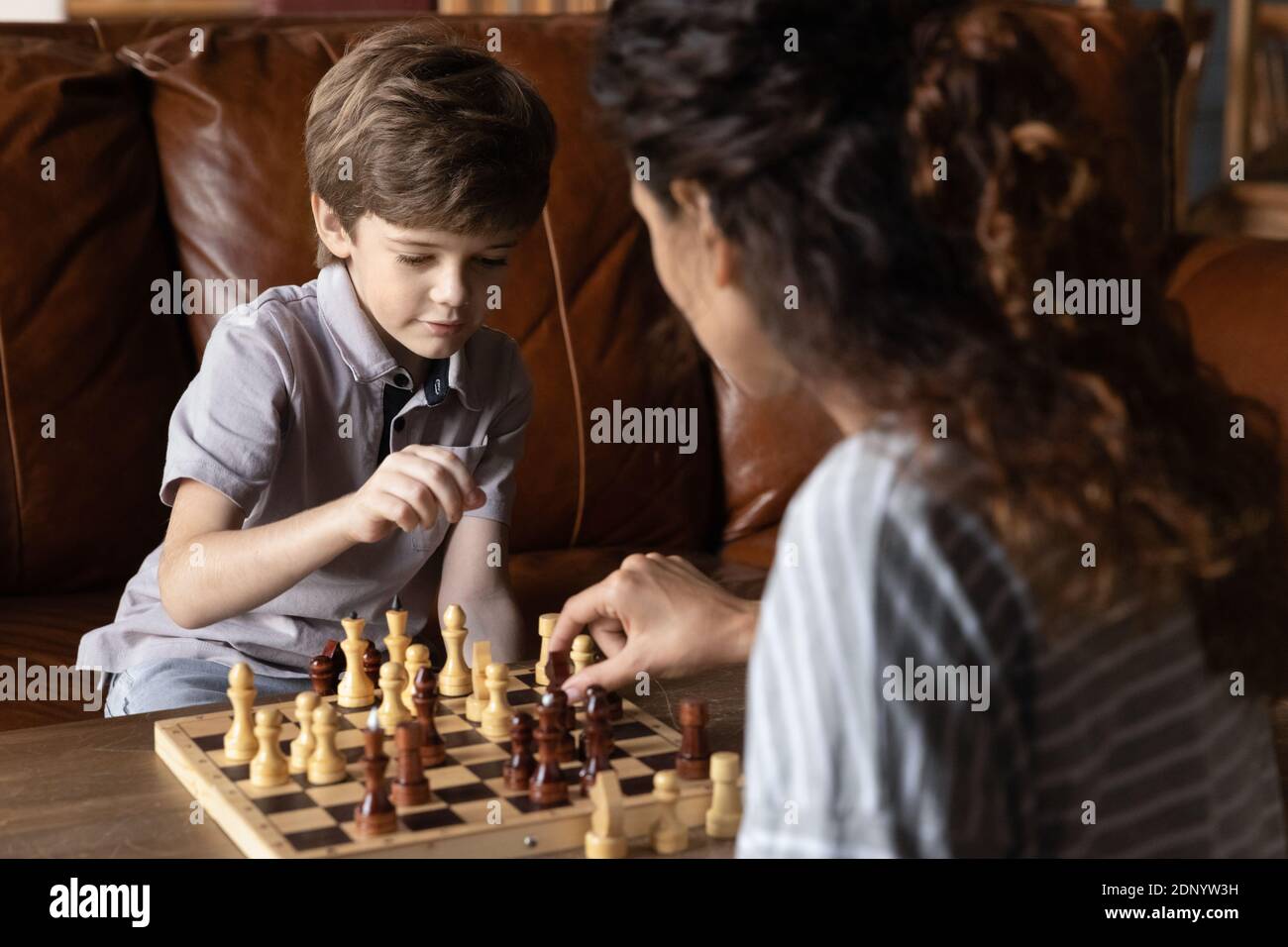 Intelligenter kleiner Junge, der Schachspiel mit tausendjähriger Mutter genießt Stockfoto