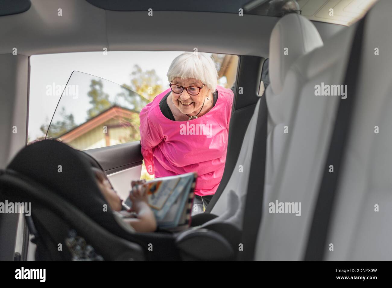 Großmutter schaut auf Baby Mädchen sitzen im Auto Stockfoto