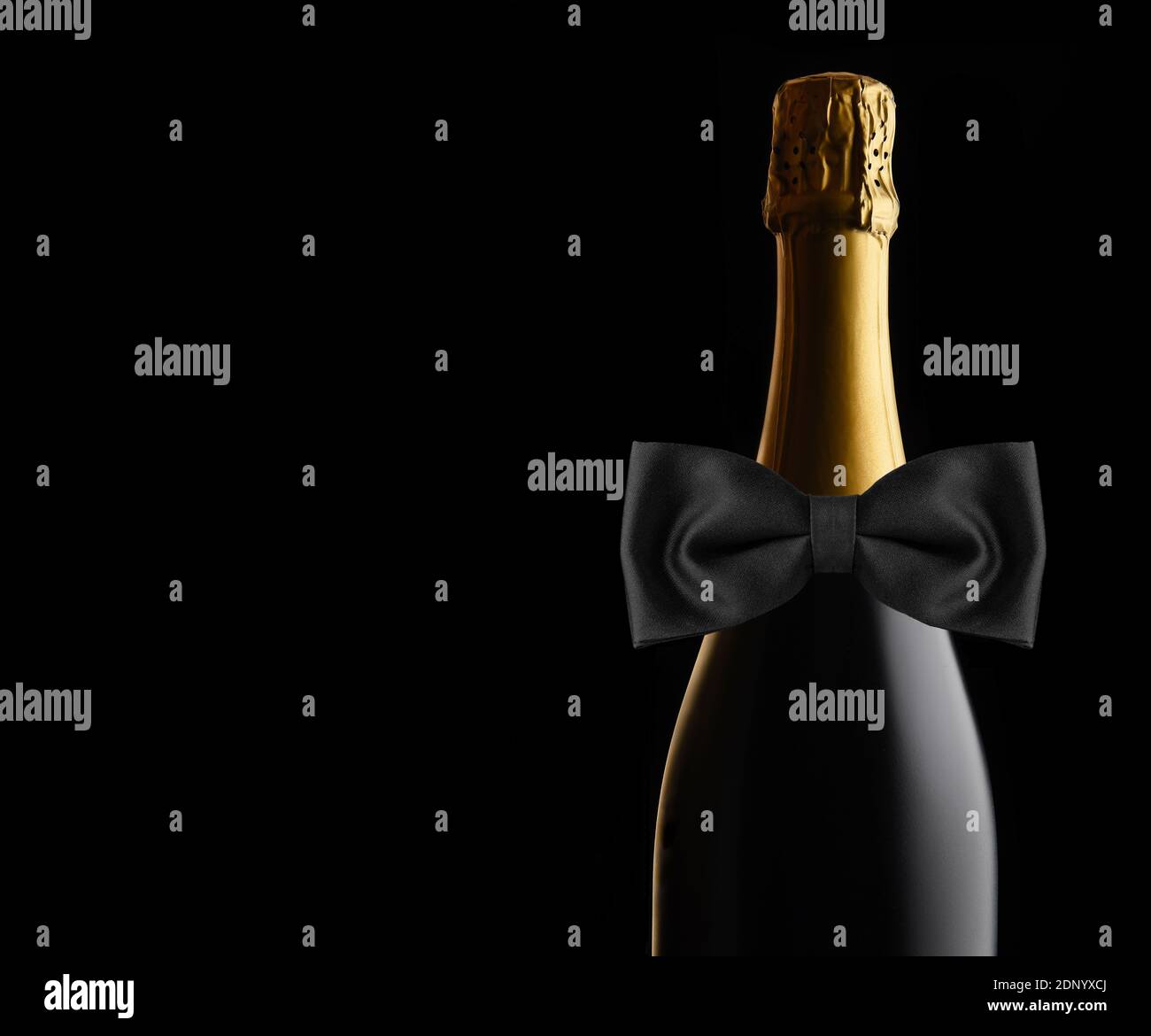 Nahaufnahme einer ungeöffneten Flasche Champagner auf schwarzem Hintergrund mit schwarzer Fliege. Ideal für Hochzeit, Jubiläum oder Neujahr Projekte, mit c Stockfoto