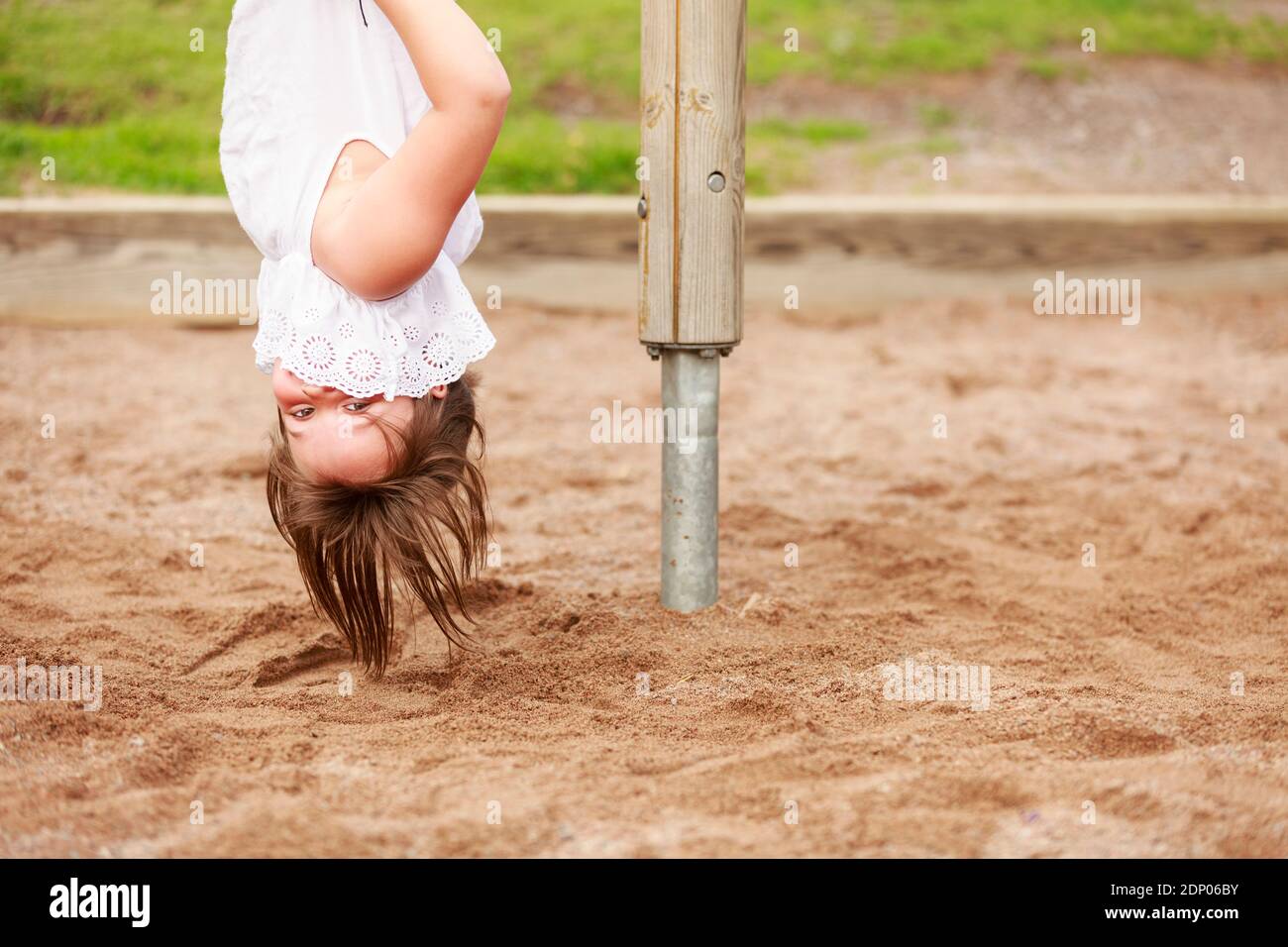 Mädchen hängend Kopf nach unten und Blick auf die Kamera Stockfoto