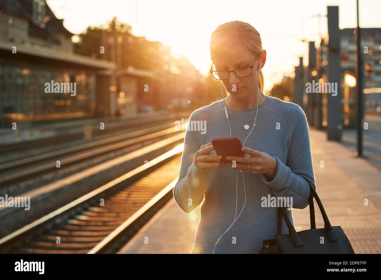 Frau mit Handy am Bahnhof Stockfoto