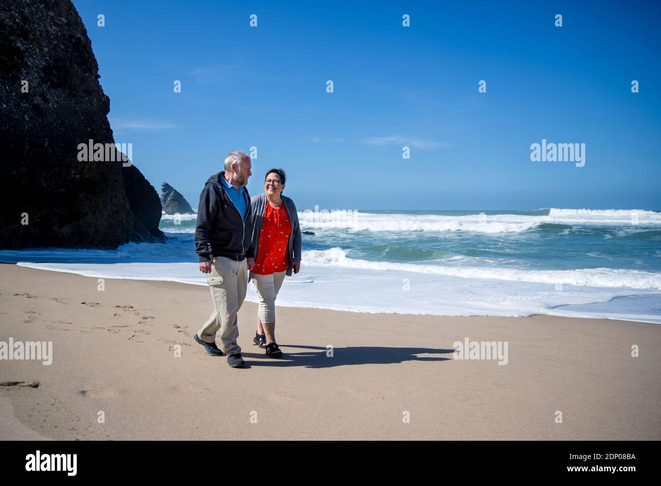 Lächelnde paar zu Fuß am Strand Stockfoto