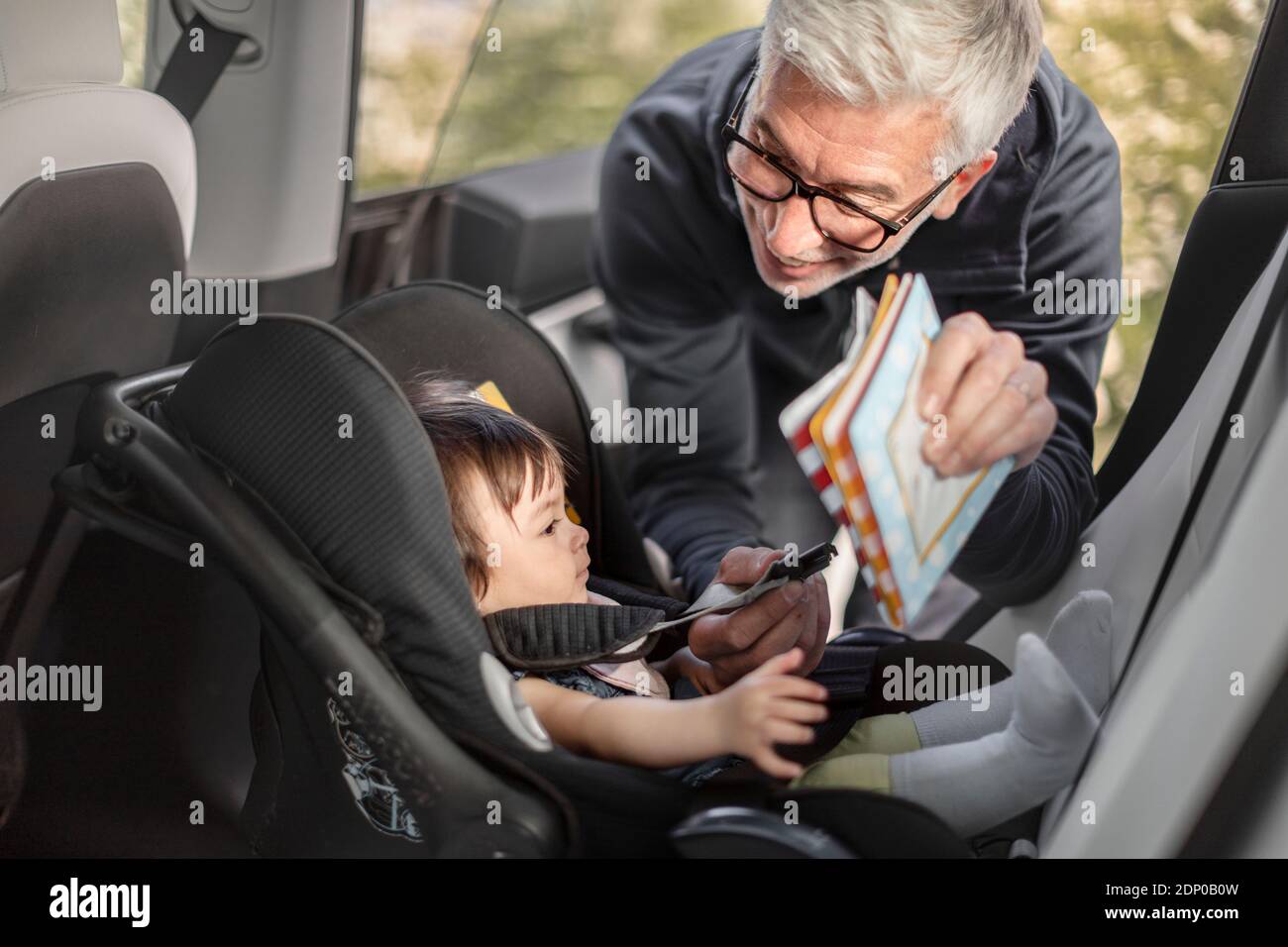 Großvater Befestigung Baby Mädchen in Auto-Sicherheit Sitz Stockfoto