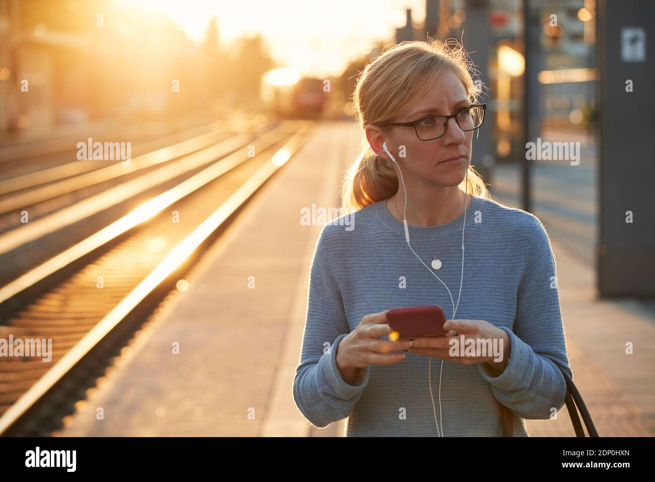 Frau mit Handy am Bahnhof Stockfoto