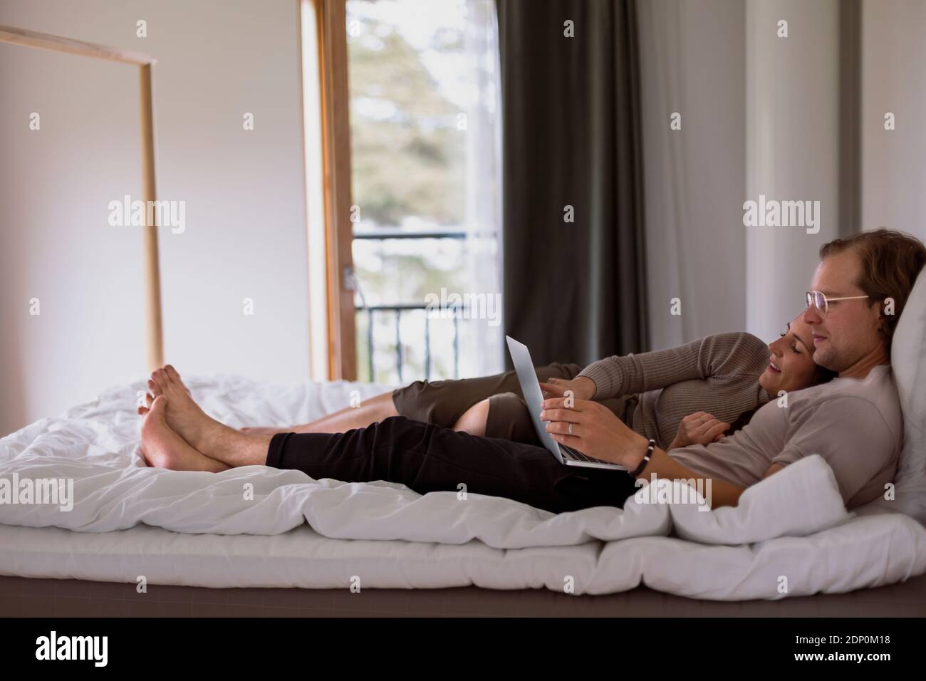 Ein Paar auf dem Bett schaute auf den Laptop Stockfoto
