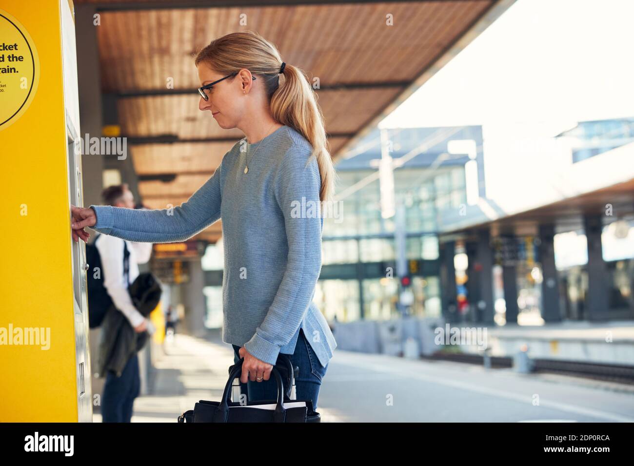 Frau, die den Ticketautomaten am Bahnhof benutzt Stockfoto