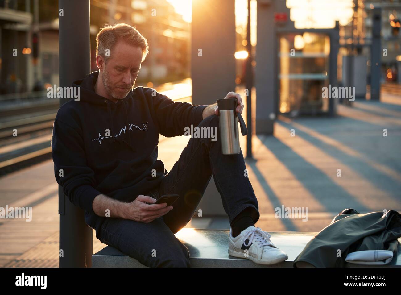 Mann mit Handy am Bahnhof Stockfoto