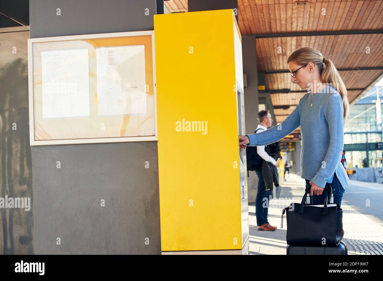 Frau, die den Ticketautomaten am Bahnhof benutzt Stockfoto