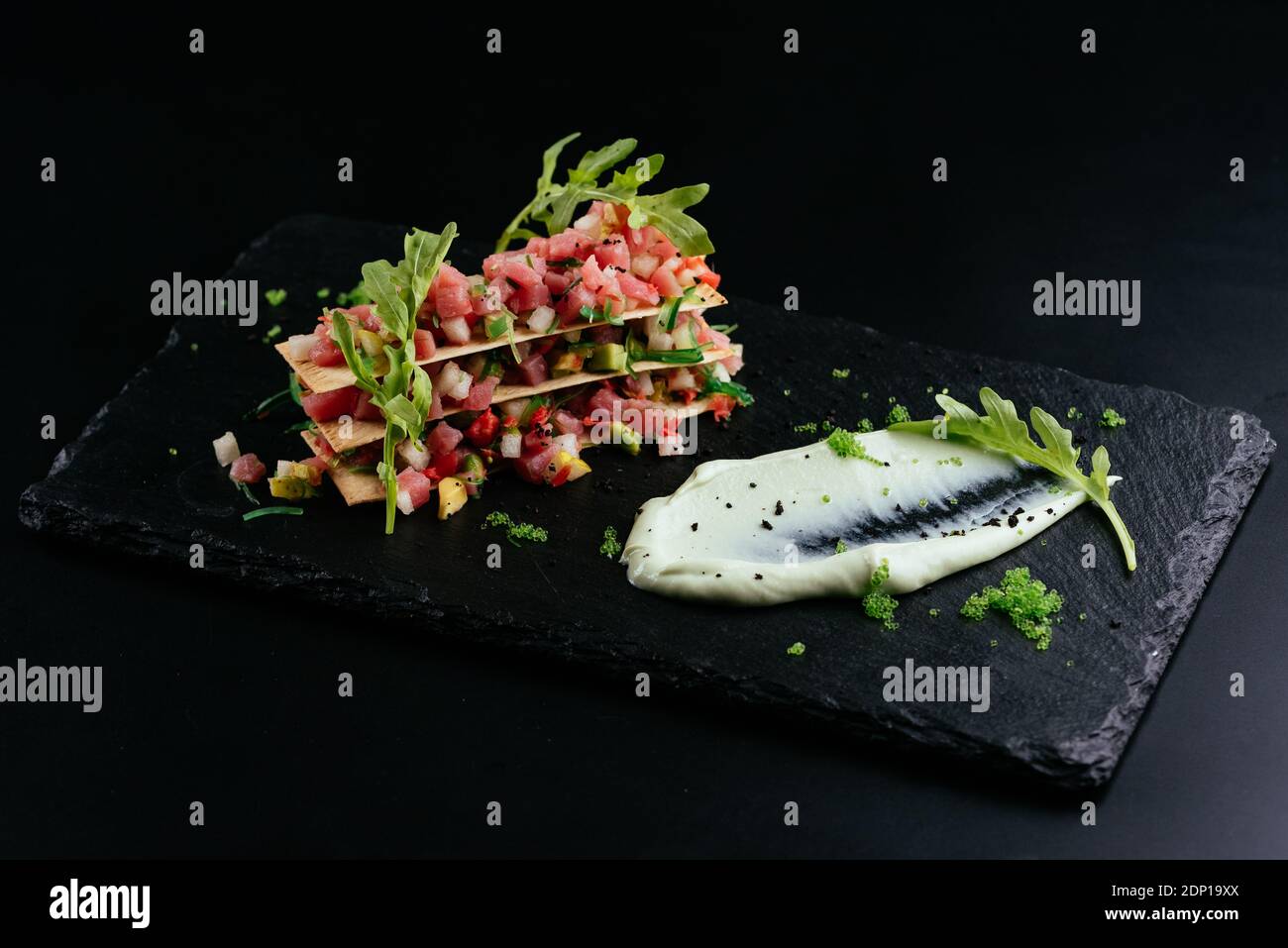 salmon tartare with white sauce on a black background Stockfoto