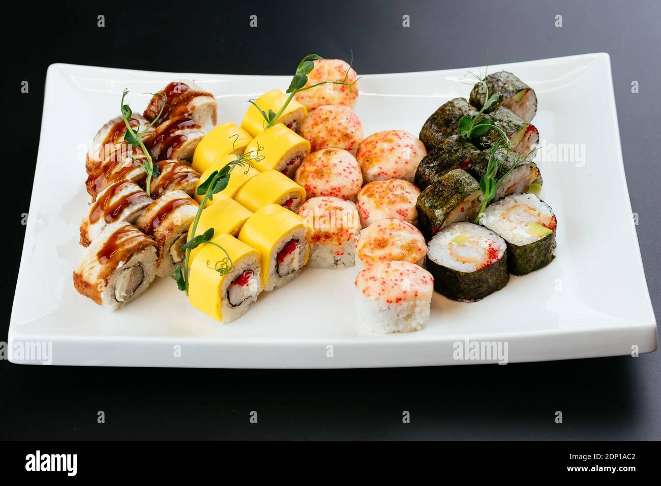 Japanische Sushi-Sets auf weißem Teller und schwarzem Hintergrund Stockfoto