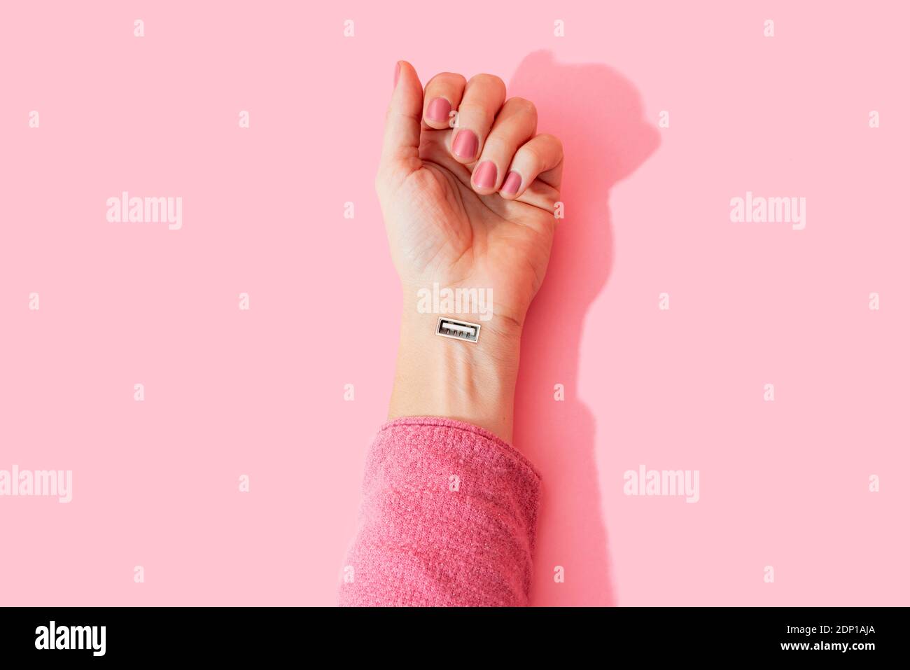 Zugeschnittenes Bild von Frau Hand mit USB-Anschluss gegen rosa Wand Stockfoto