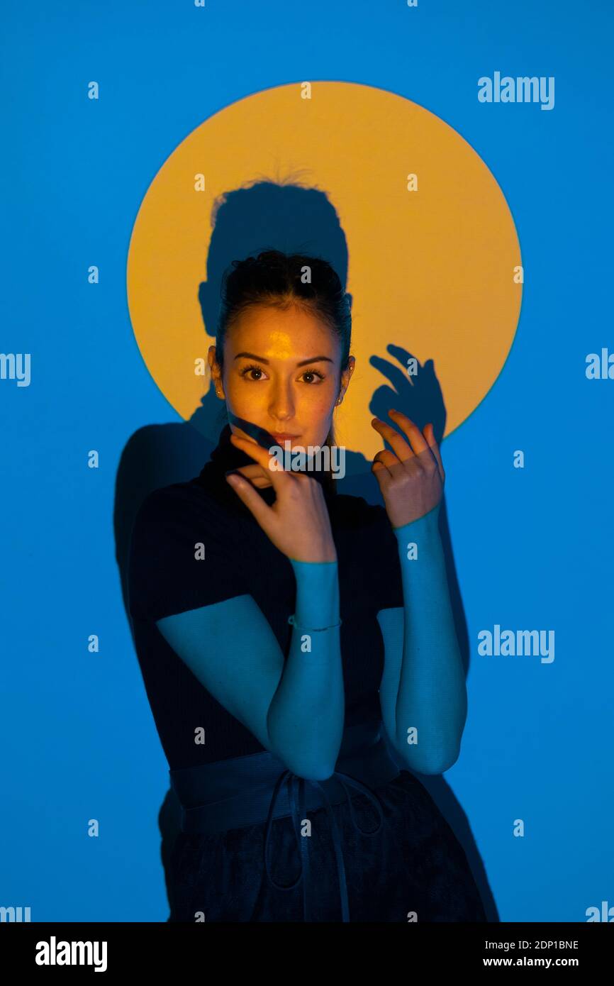 Junge Frau, die sich in blauem Licht vor Gelb bewegt Kreis Stockfoto