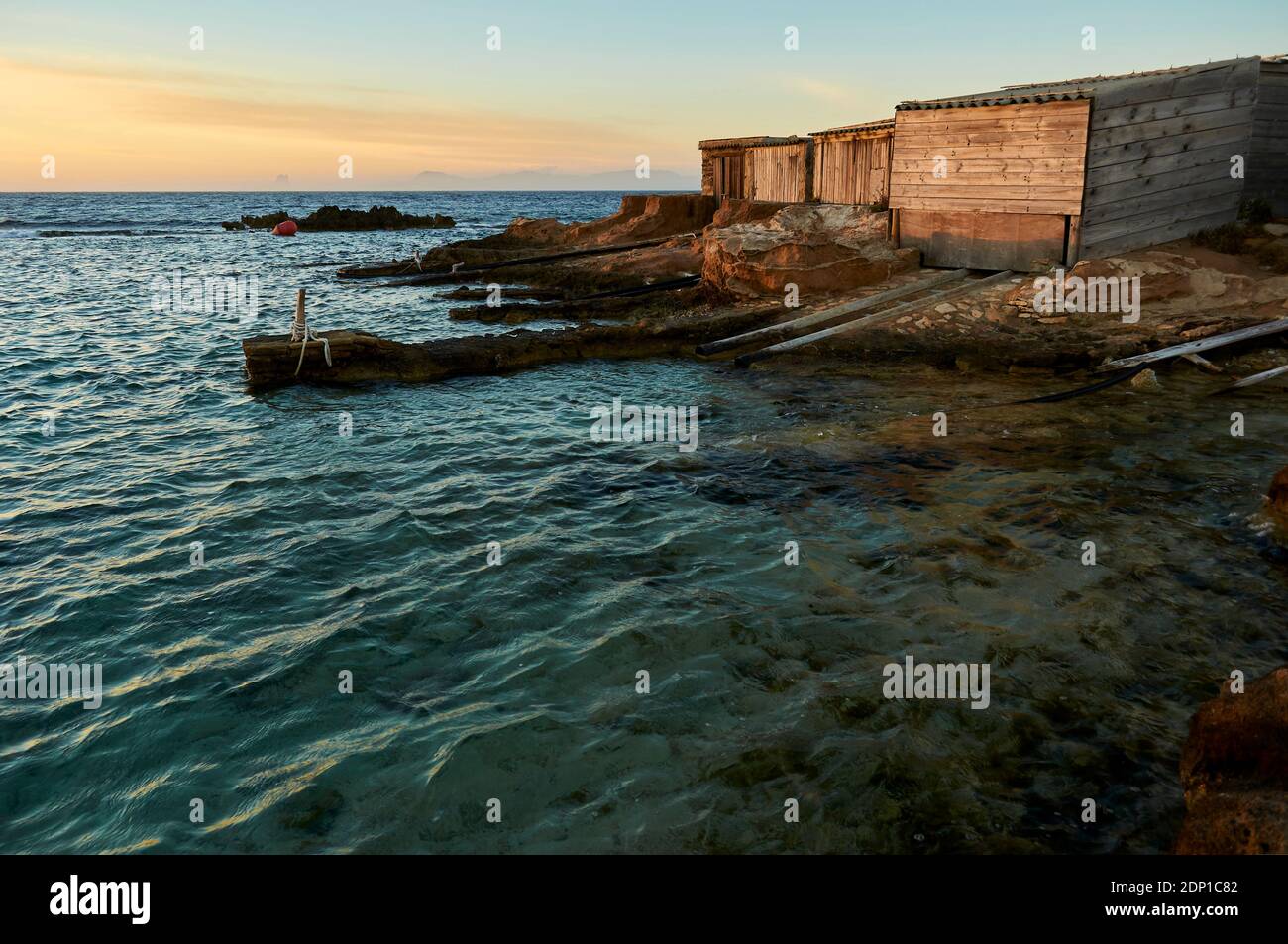 Traditionelle Bootshäuser, die Escars genannt werden, bei Sonnenuntergang in der Nähe der Meereslagune Estany des Peix im Naturpark Ses Salines (Formentera, Mittelmeer, Spanien) Stockfoto Traditionelle Bootshäuser, die Escars genannt werden, bei Sonnenuntergang in der Nähe der Meereslagune Estany des Peix im Naturpark Ses Salines (Formentera, Mittelmeer, Spanien) Stockfoto