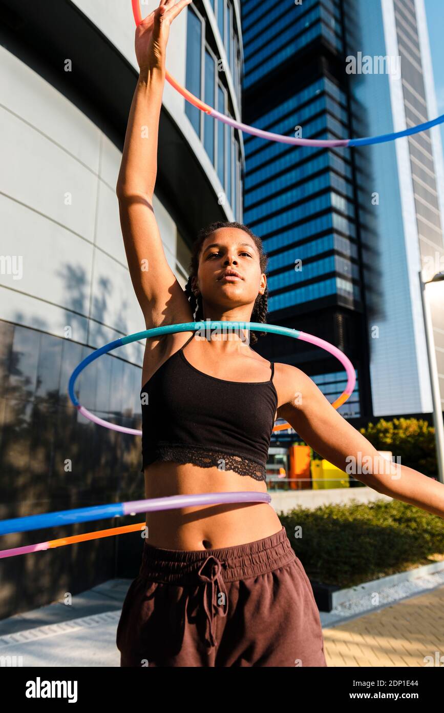 Sportliche Frau beim Training mit Kunststoffreifen außerhalb von Bürogebäuden Stockfoto