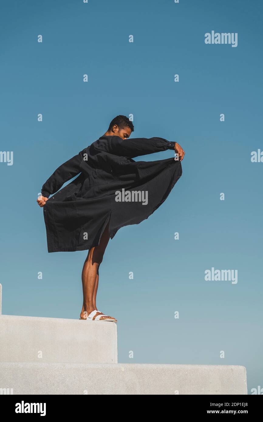 Junger Mann, der schwarze Kaftan trägt, tritt im Freien auf Stockfoto